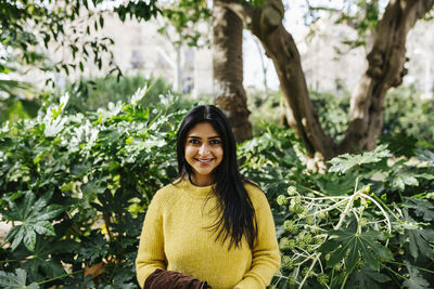 Portrait of smiling young woman against plants