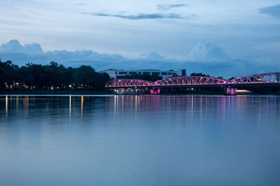Illuminated bridge over river against sky in city