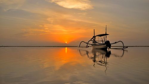 Silhouette boat in sea against sky during sunset