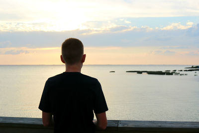 Rear view of boy looking at sea against sky