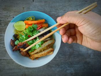 Midsection of person holding food in bowl on table