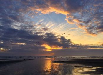 Scenic view of sea against cloudy sky at sunset