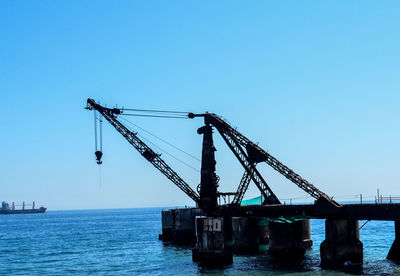 Cranes at construction site against clear blue sky