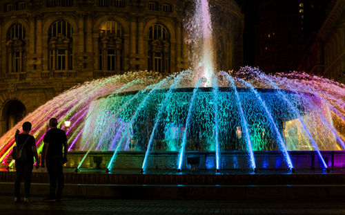 People at illuminated fountain in city at night