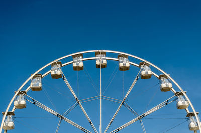 Low angle view of ferris wheel against clear blue sky