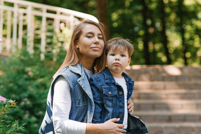 Mother with a three-year-old child playing outdoors on a sunny day in a city park