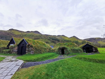 House on field by building against sky