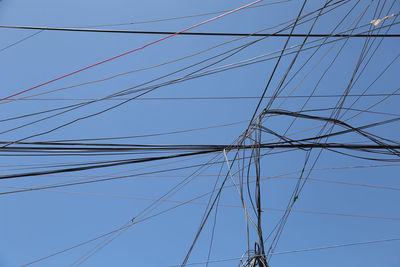Low angle view of power lines against clear blue sky