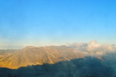 Scenic view of volcanic mountain against blue sky