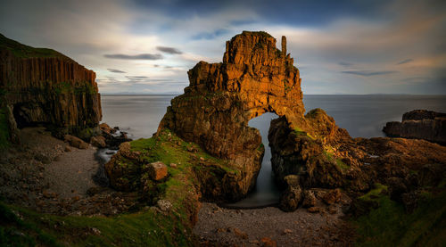 Rock formations by sea against sky during sunset