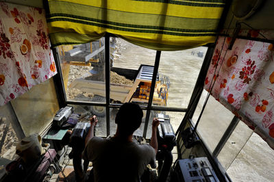 Worker operating crane from cabin at construction site