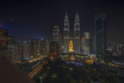 Petronas towers in city against sky at night