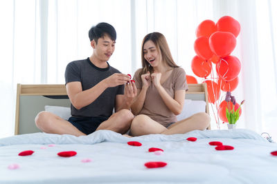 Couple sitting on red balloons