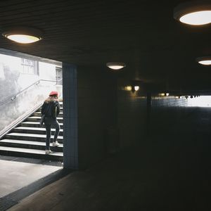 Rear view of woman walking in illuminated corridor