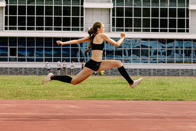 Full length of young woman exercising on field