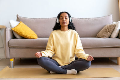 Portrait of young woman sitting on sofa at home