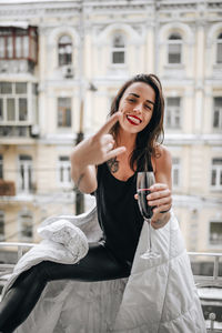 Portrait of smiling young woman standing against building in city