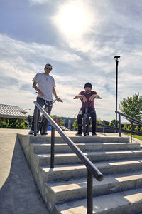 Portrait of riders with bmx bikes at skateboard park during sunny day