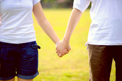 Midsection of couple holding hands