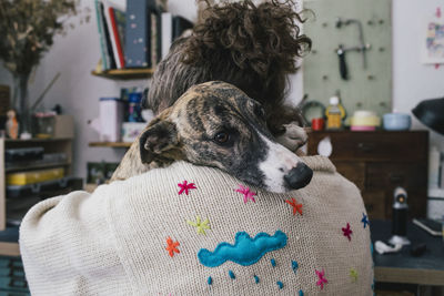 Dog resting on female owner shoulder at home