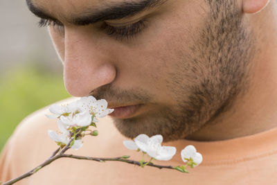 Close-up of young man against white flowering plant