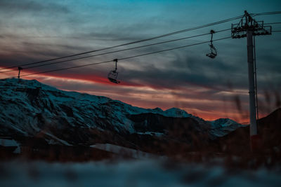 Low angle view of snowcapped mountain against dramatic sky during sunset