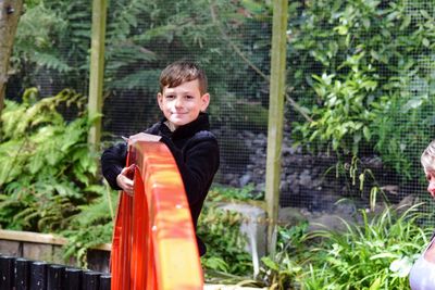 Portrait of smiling boy standing by plants in garden