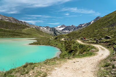 Scenic view of road by mountains against sky