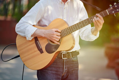 Midsection of man playing guitar