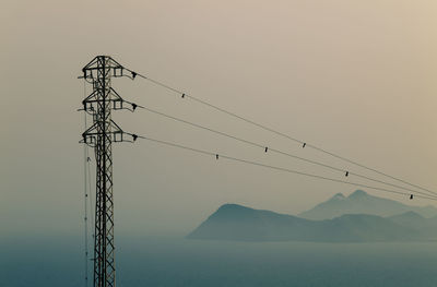 Electricity pylon by mountains against clear sky during sunset in gabo de gata nature park, spain