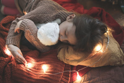 Sleeping baby girl hugging a white cat with ears, a cozy childhood and home environment,