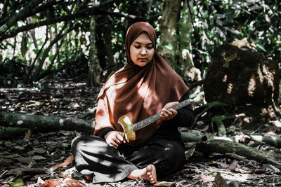 Young woman sitting on tree in forest