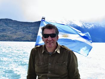 Portrait of young man wearing sunglasses while standing against sea