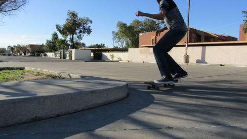 Low section of man skateboarding on street