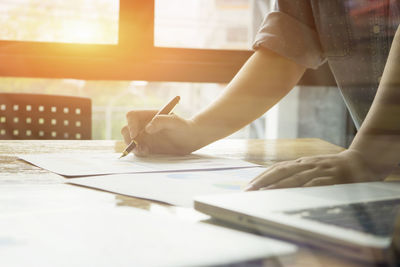 Midsection of woman analyzing chart at office desk