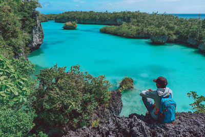 Man sitting on rock by sea