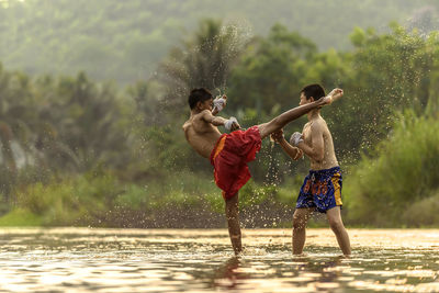 Shirtless boys playing in swamp