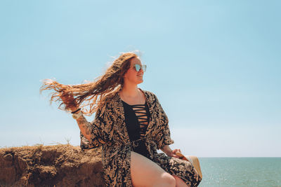 Happy woman wearing hat and glasses at the seaside enjoying summer weather