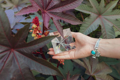 Cropped hand of woman holding pyramid crystal outdoors