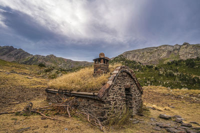 Old ruin on field by mountain against sky