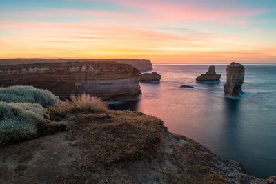 Rocks on sea against sky during sunset