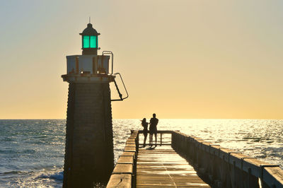 Silhouette man walking on pier against sky during sunset. capbreton 