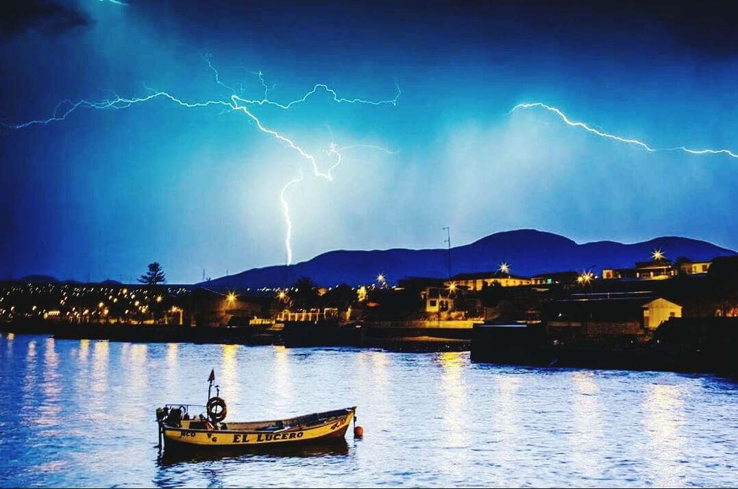 illuminated, night, water, sky, waterfront, river, building exterior, scenics, blue, beauty in nature, nautical vessel, built structure, reflection, mountain, architecture, lake, nature, sea, tranquility, tranquil scene