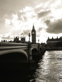 Bridge over river in city against sky