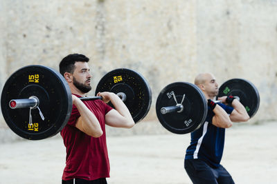 Two weightlifters lifting weights in an urban environment.