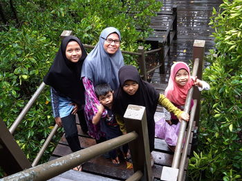 Portrait of smiling family in hijab standing on staircase