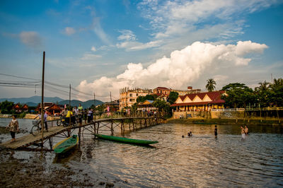 People traveling on footbridge over river