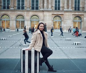 Full length portrait of woman sitting in city