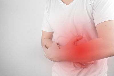 Midsection of man with stomachache standing against white background