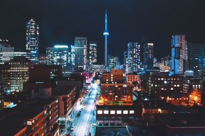 Illuminated cn tower amidst buildings at night in city